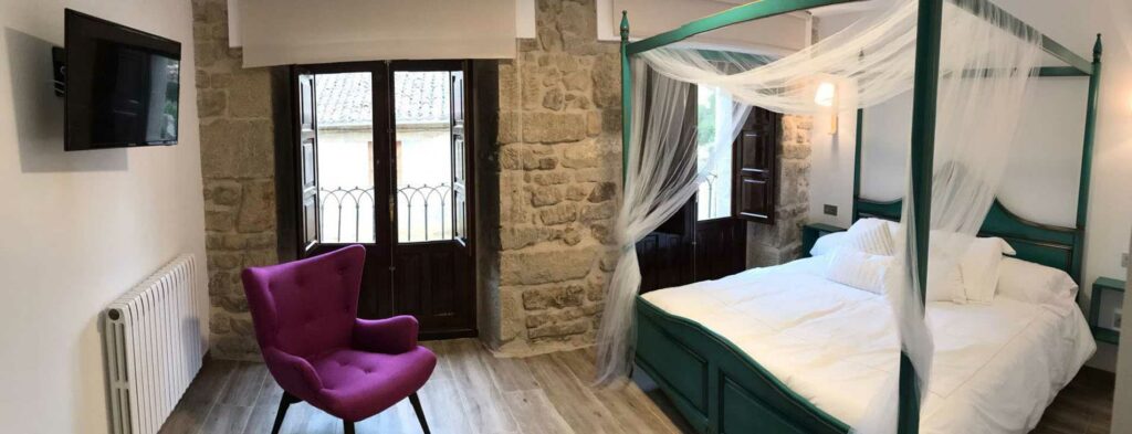 Chambre Santa Lucía avec lit à baldaquin et murs en pierre à La Casona de Alútiz